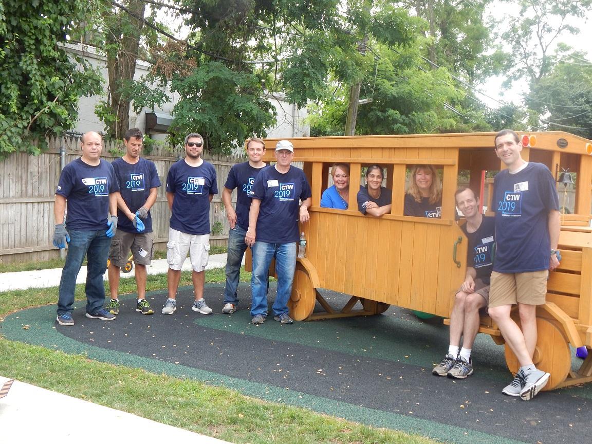 Goldman Sachs volunteers in front of playground school bus